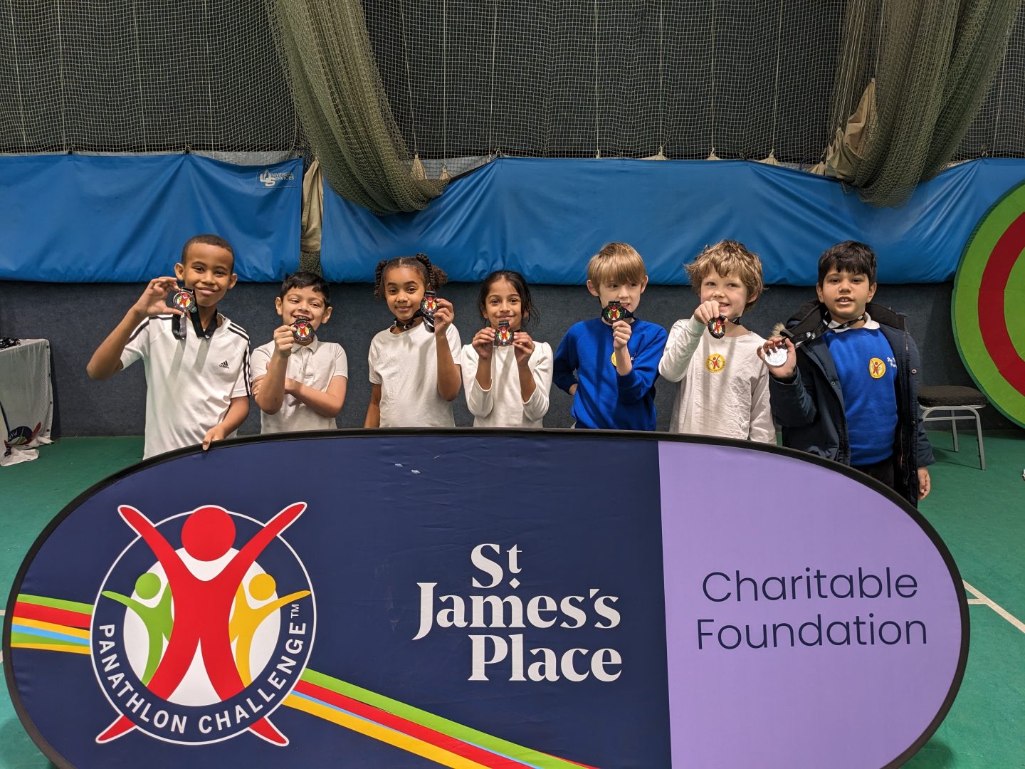 A group of children holding their medals in front of the Panathlon banner.