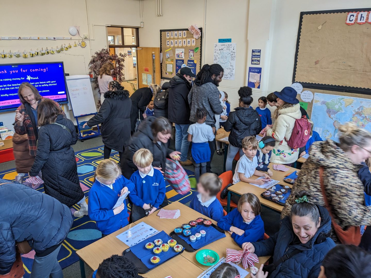 Parents and children buying and selling cakes in a classroom.